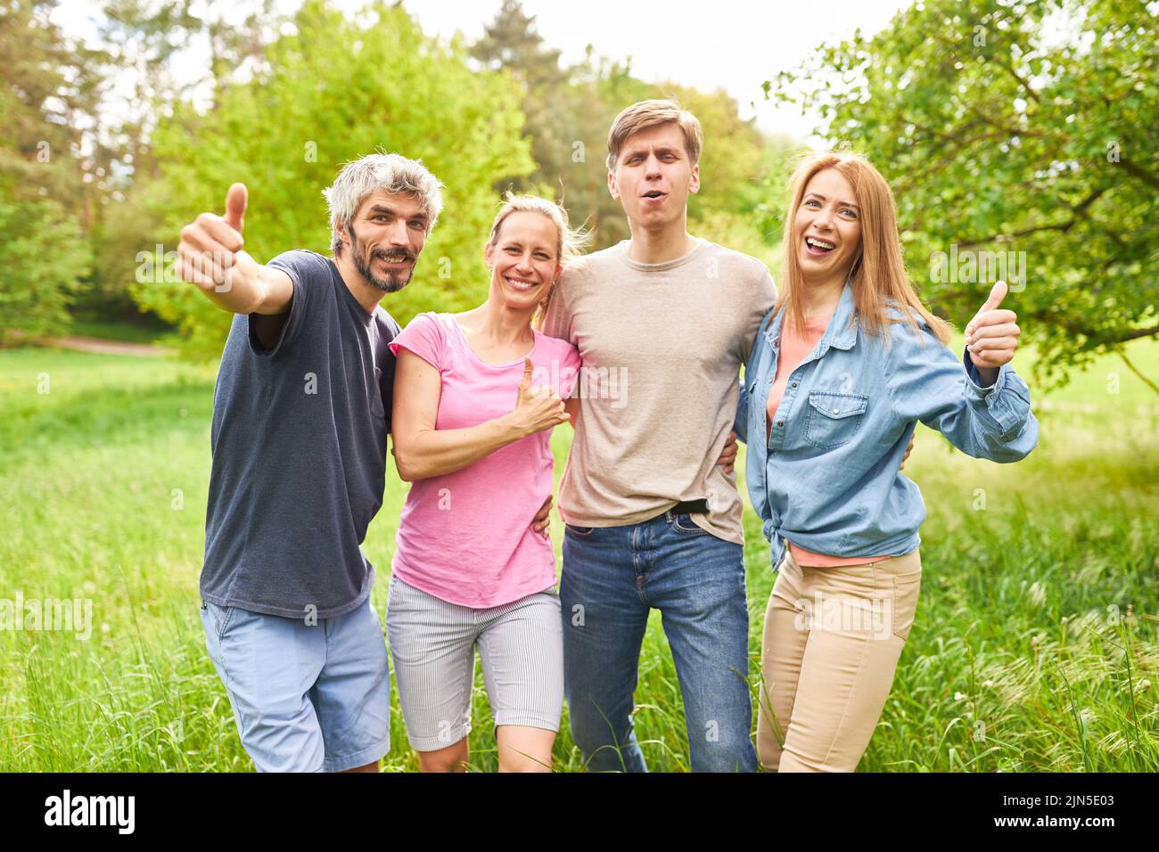 Group of young people with thumbs up on summer vacation on a green meadow Stock Photo
