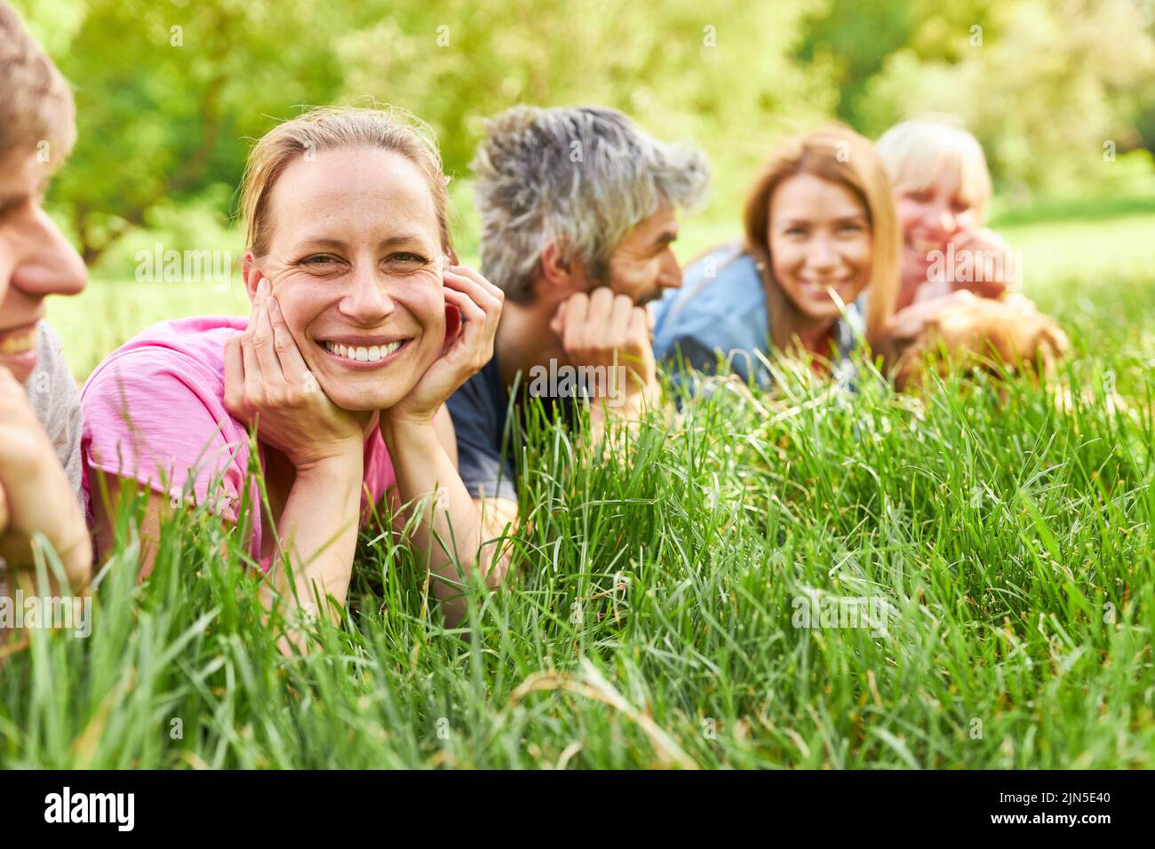 Happy young woman relaxing together with friends in the grass on a summer meadow Stock Photo