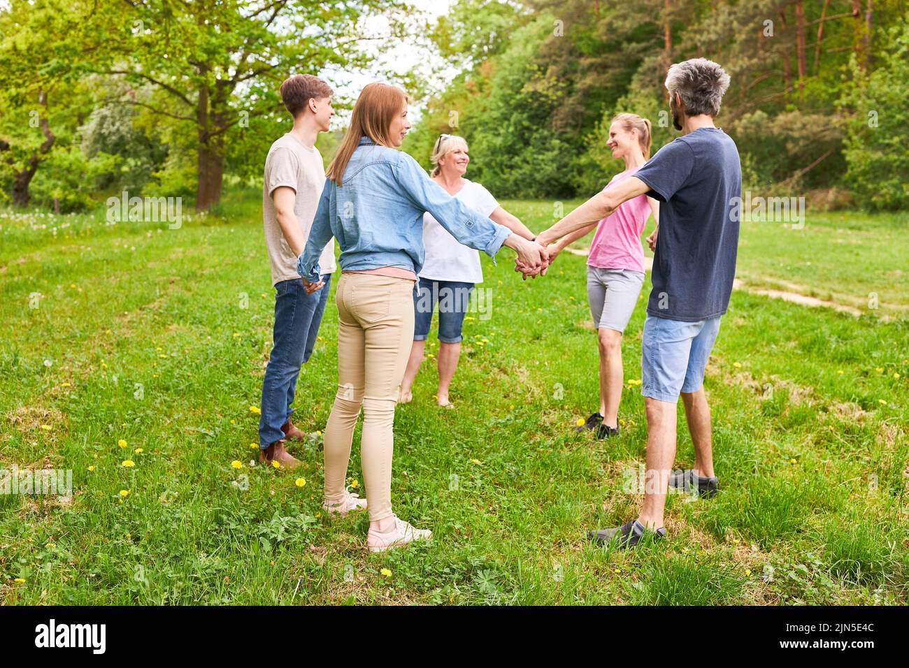 Young people stand in a circle and hold hands for team building and team spirit Stock Photo
