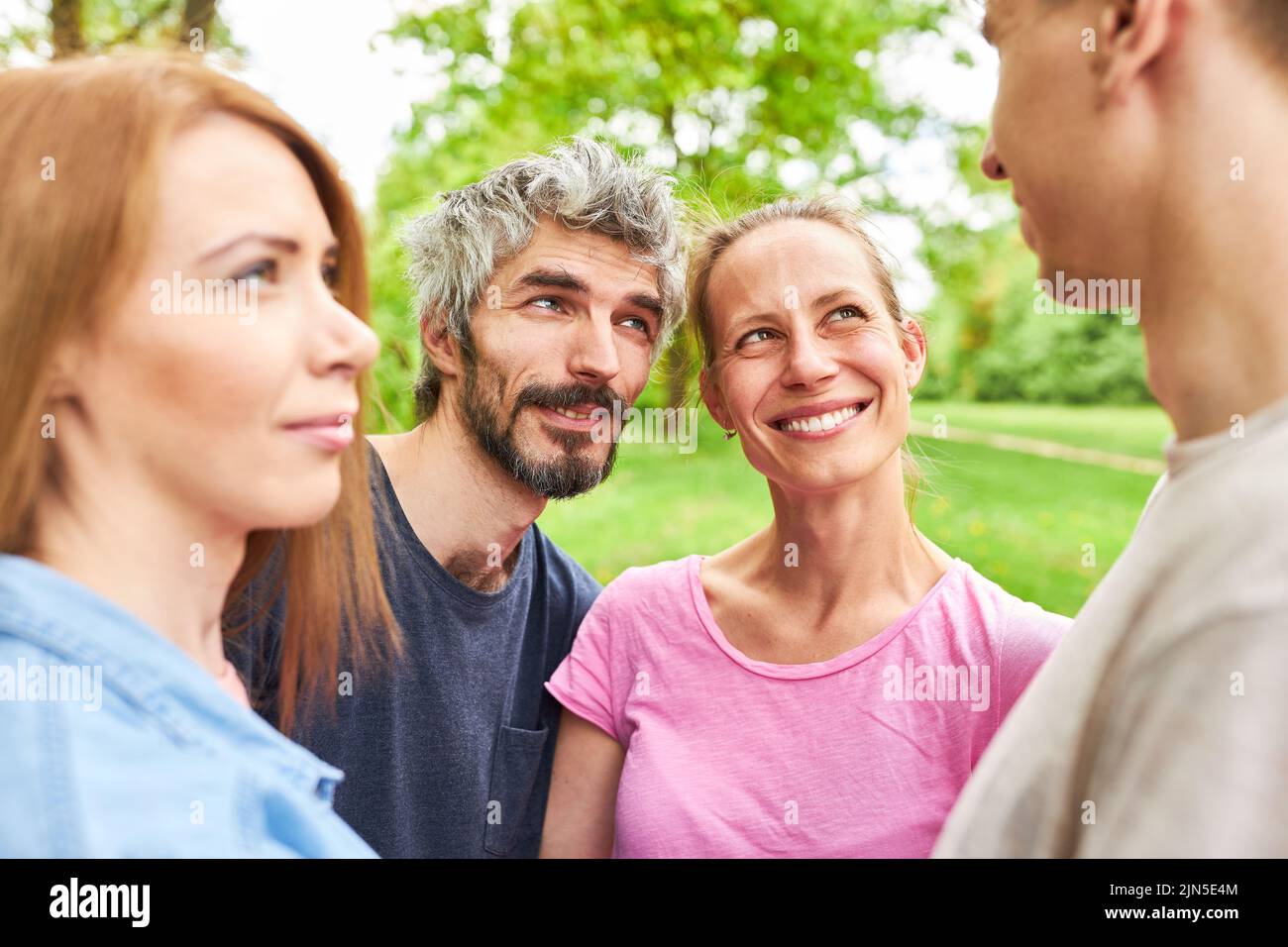 Four young people as friends are talking relaxed in the park on summer vacation Stock Photo