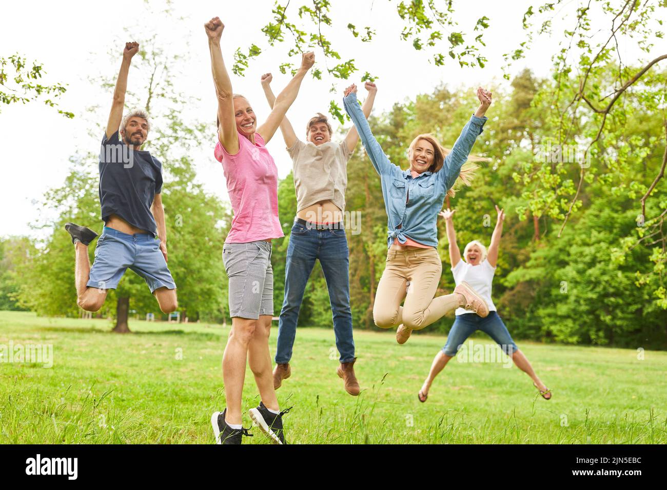 Sporty young people jump in the air on a meadow for joie de vivre and fitness Stock Photo