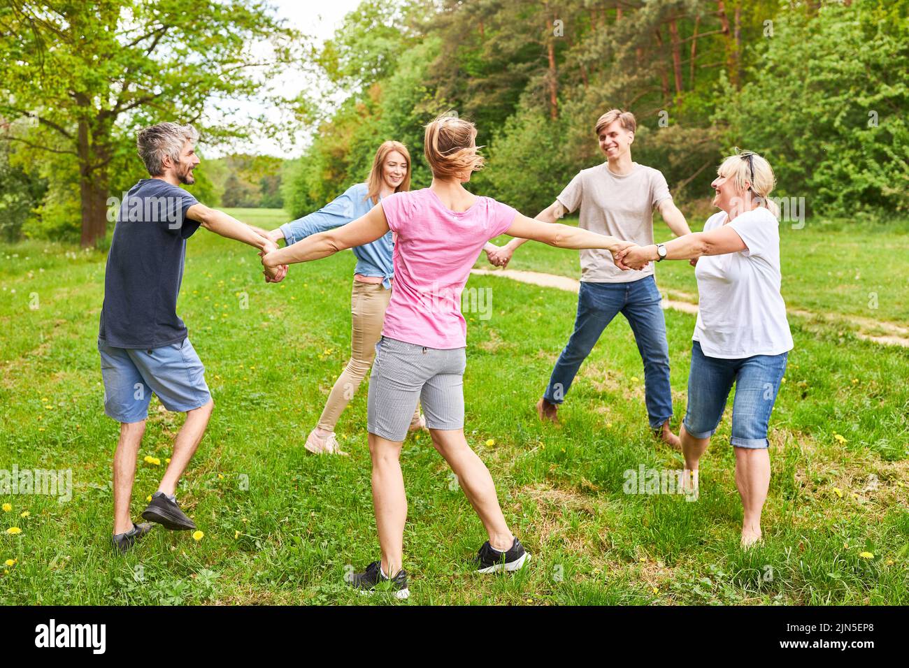 Young people standing in circle and holding hands at team building