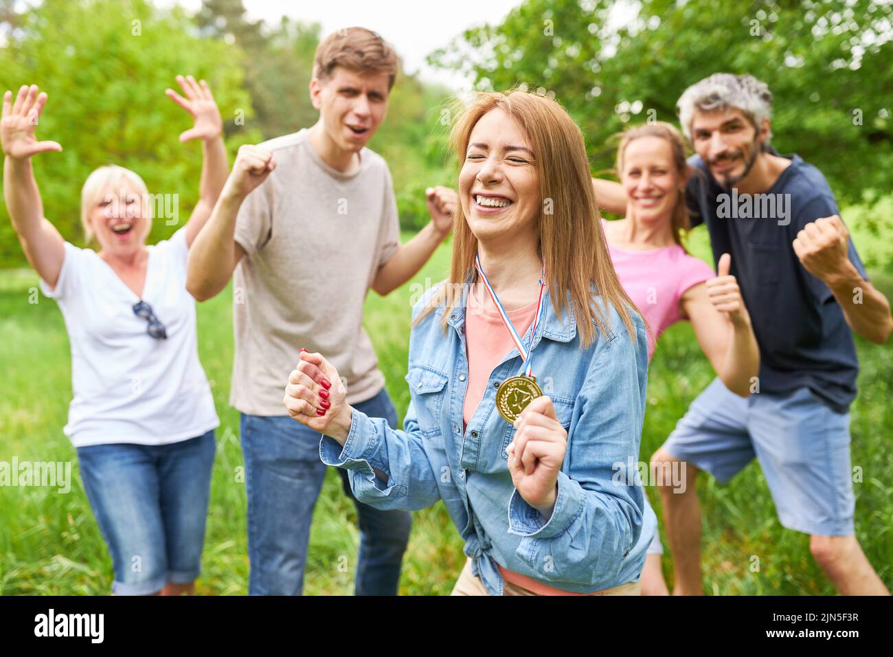 Young woman with a medal is happy and cheers with her friends as a team on a success Stock Photo