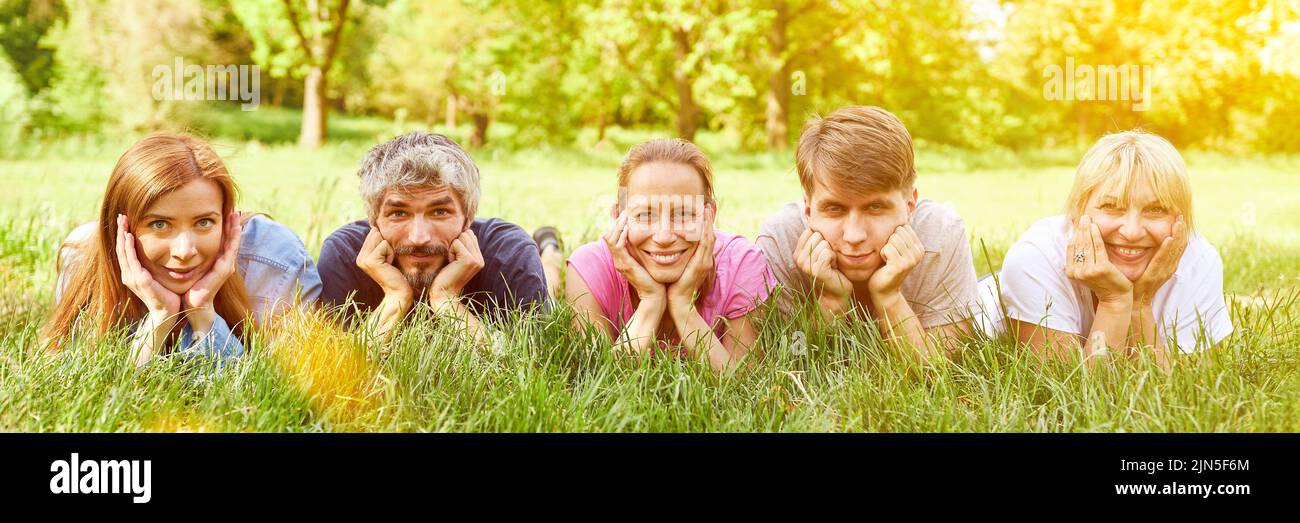 Happy group of friends lie together side by side on a green meadow in summer Stock Photo