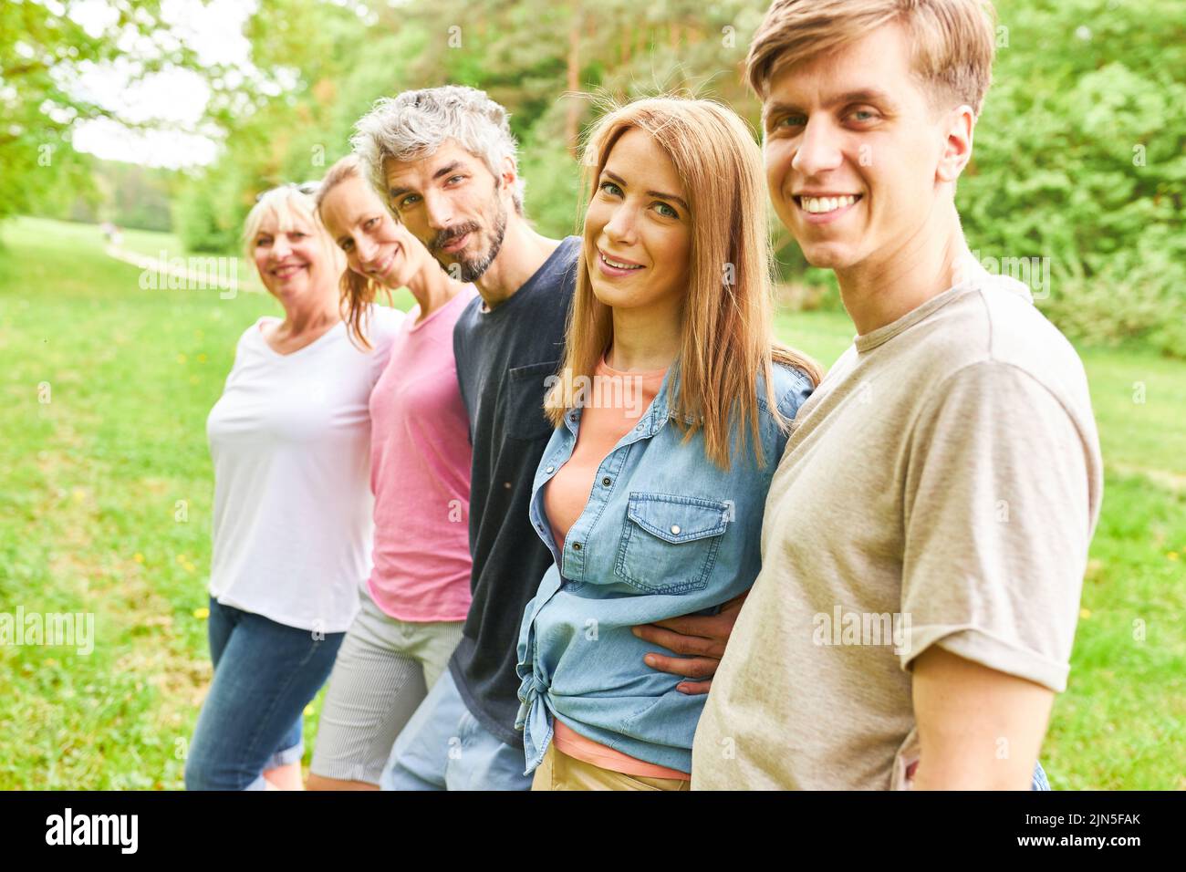 Smiling young people stand side by side in the park for friendship and