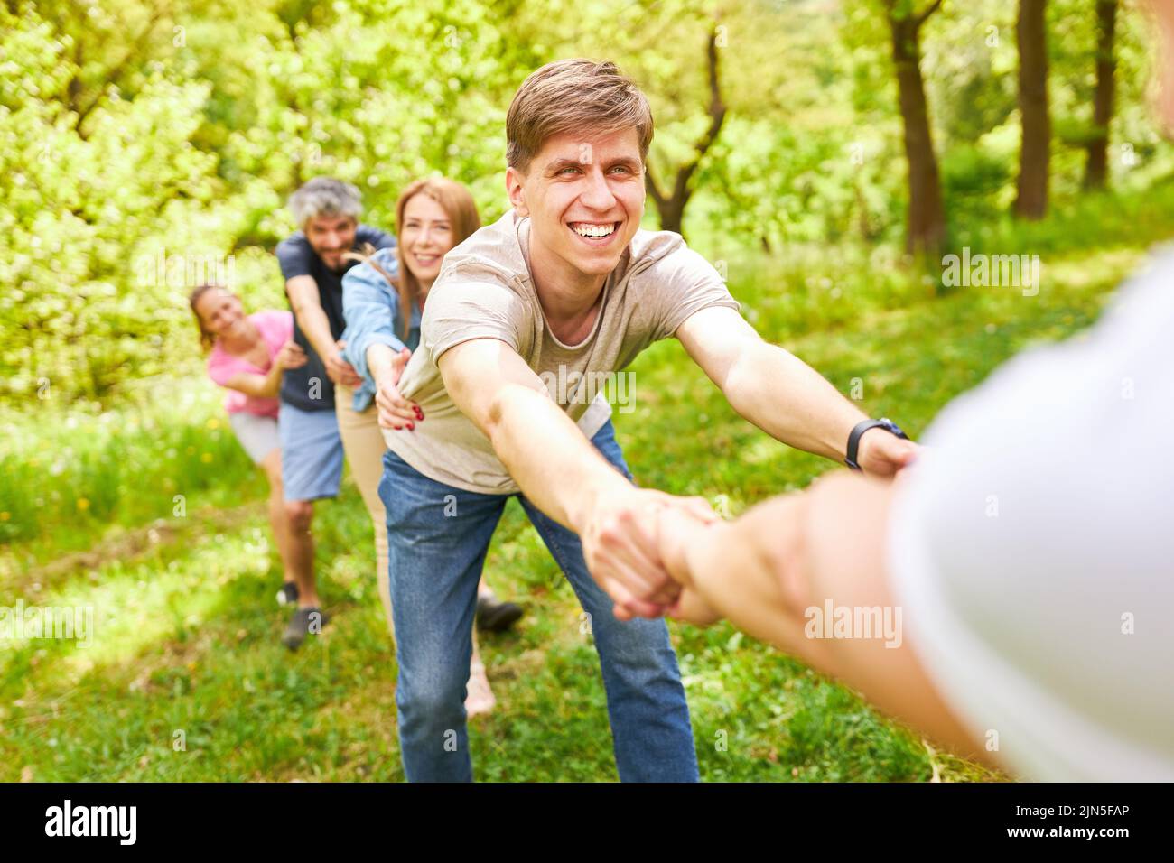 Young people pull hands at competition in team building workshop in nature Stock Photo
