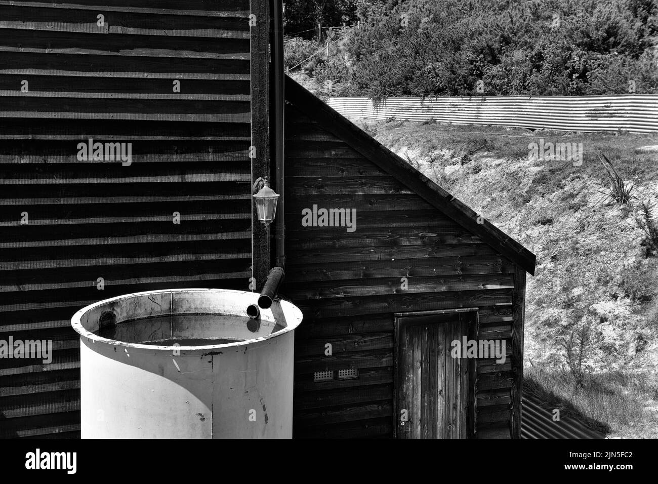 full rain water tank outside wooden barn conversion Stock Photo