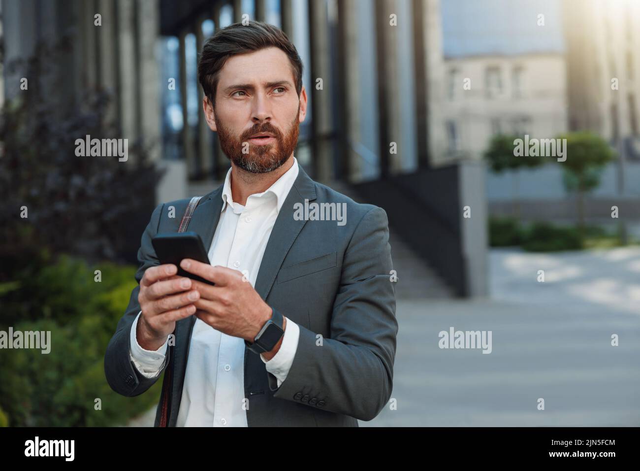 Focused Businessman in suit going home after long working day and using phone Stock Photo