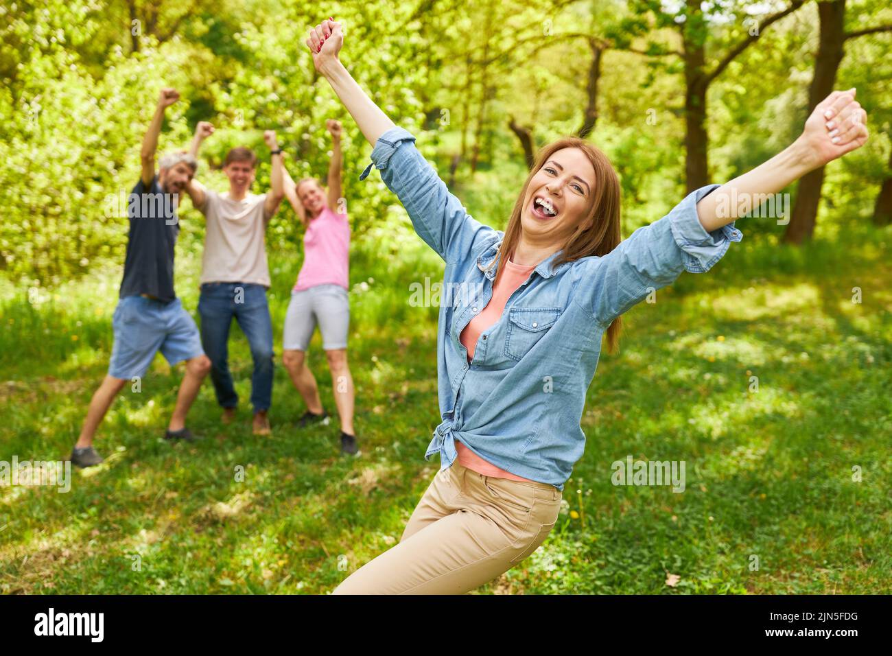 Happy young woman celebrating victory in competition with team on background Stock Photo