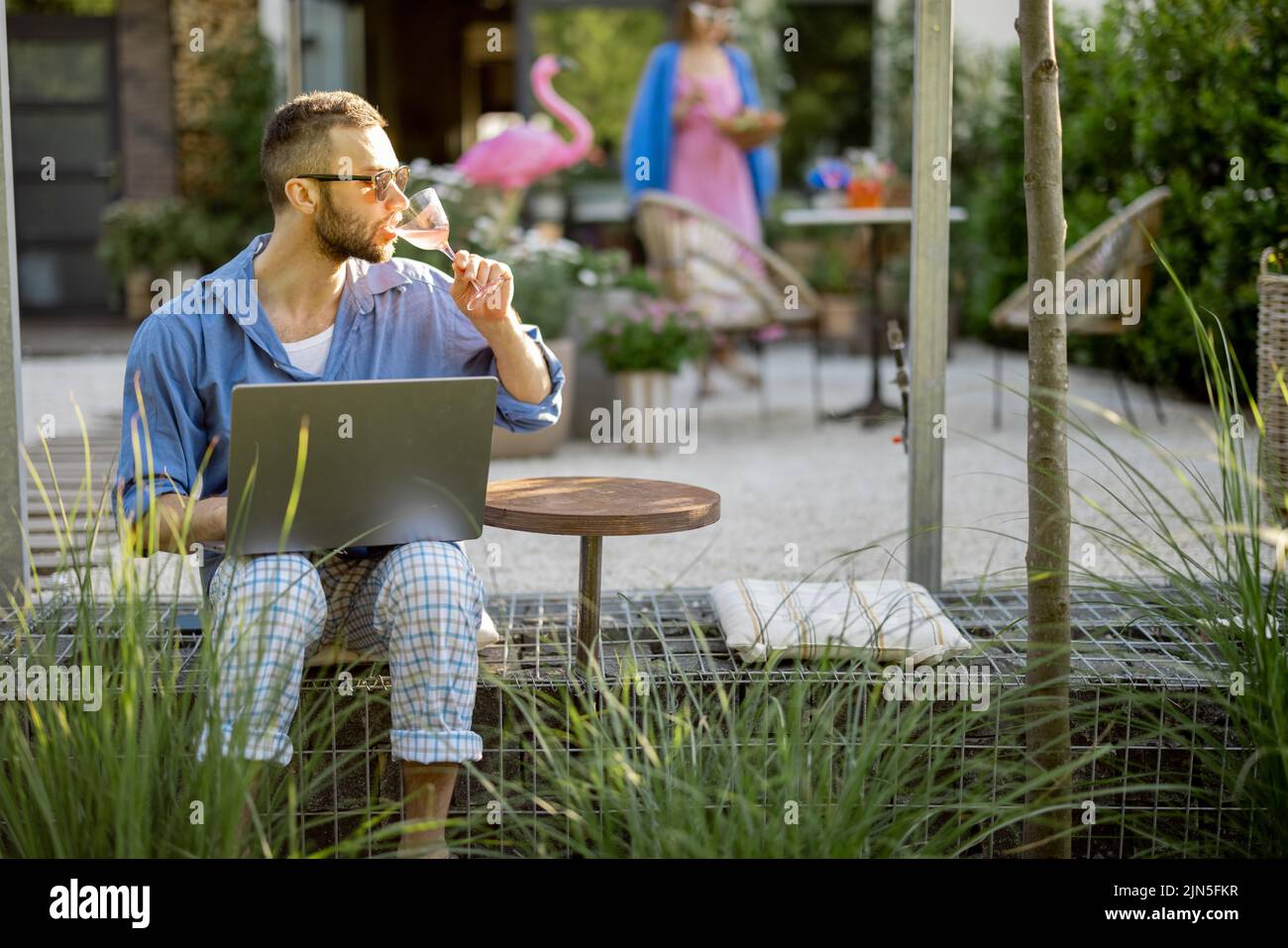 Man works on laptop while sitting at backyard Stock Photo