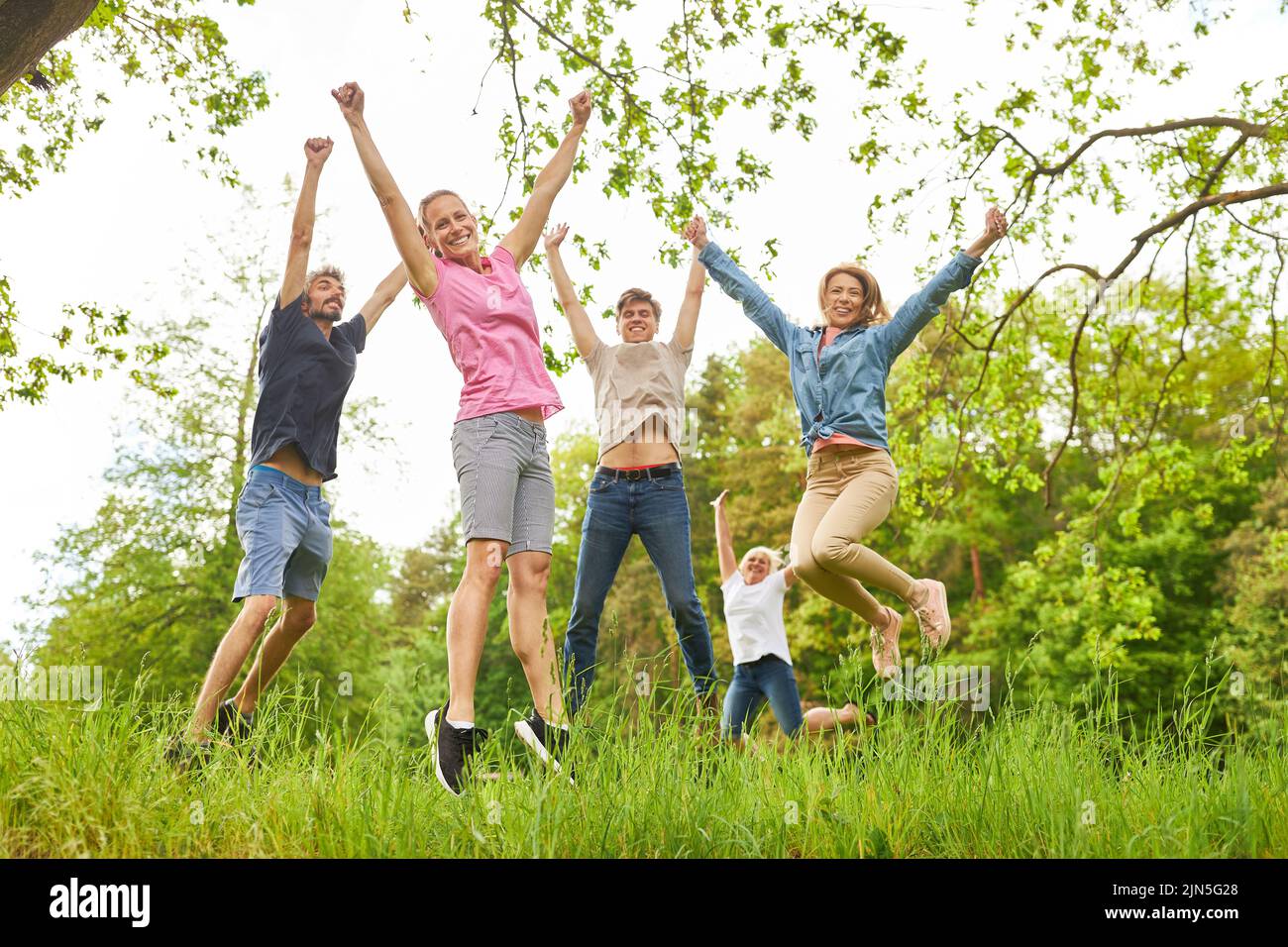 Cheerful young people jump in the air on a meadow for cheers and lightness Stock Photo