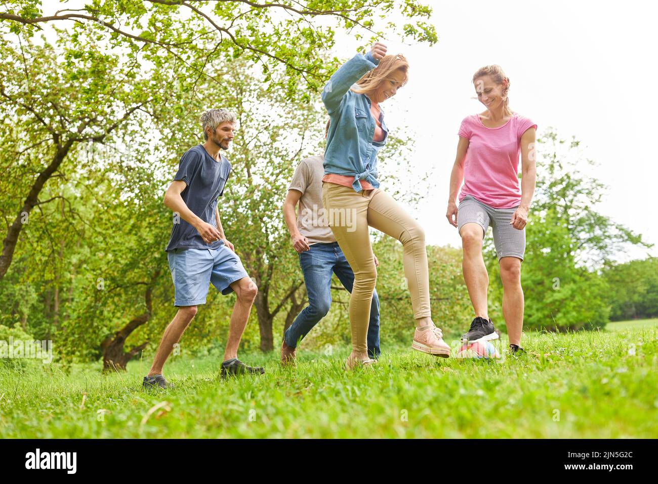 Young people have fun together playing soccer in a meadow in summer Stock Photo