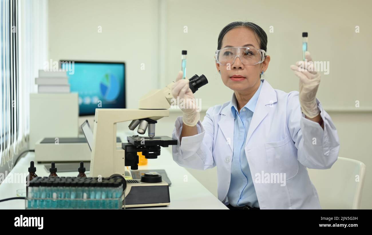 Mature female scientist working analysis with blue liquid test tube in
