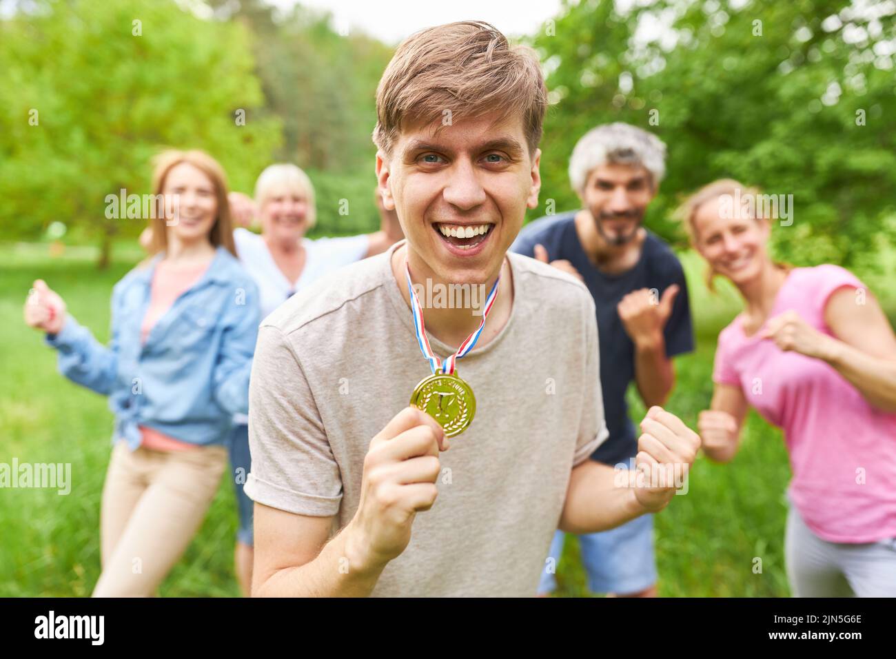 Happy man with winner medal in front of his team after a successful competition Stock Photo