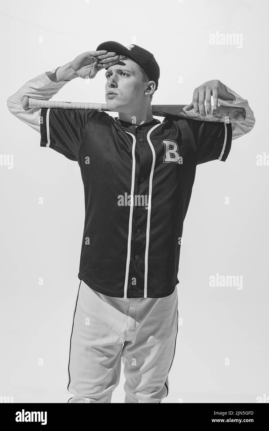 Portrait of young man, college student, baseball player in uniform posing with bat. Black and white photography Stock Photo