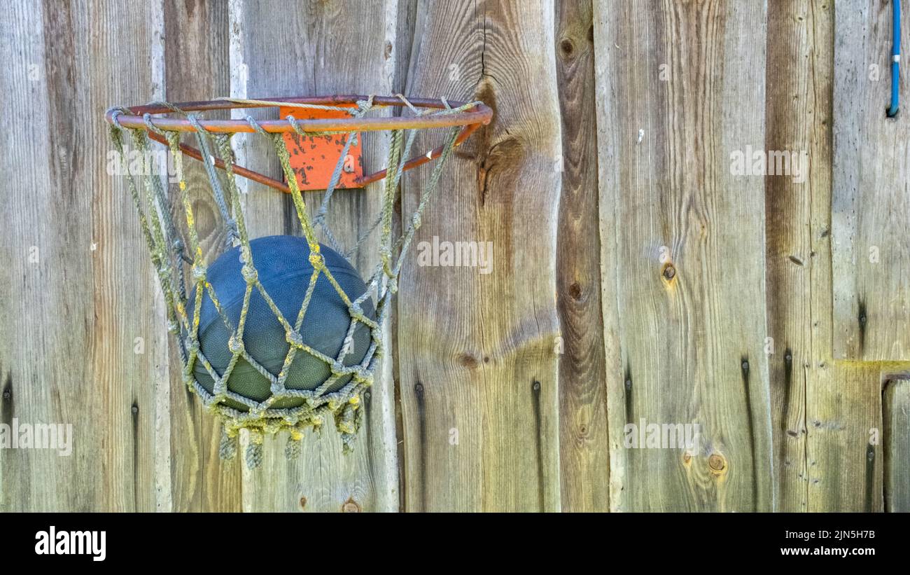 A very old basketball hoop with a ball bolted to the wooden plank wall Stock Photo Alamy