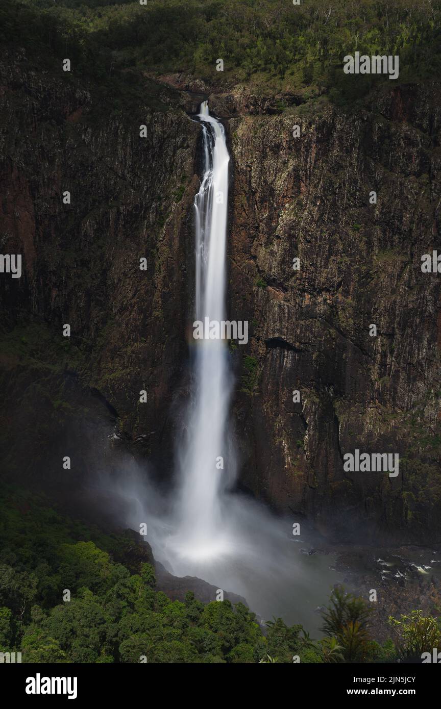 A vertical shot of a waterfall flowing down the rocks covered with ...
