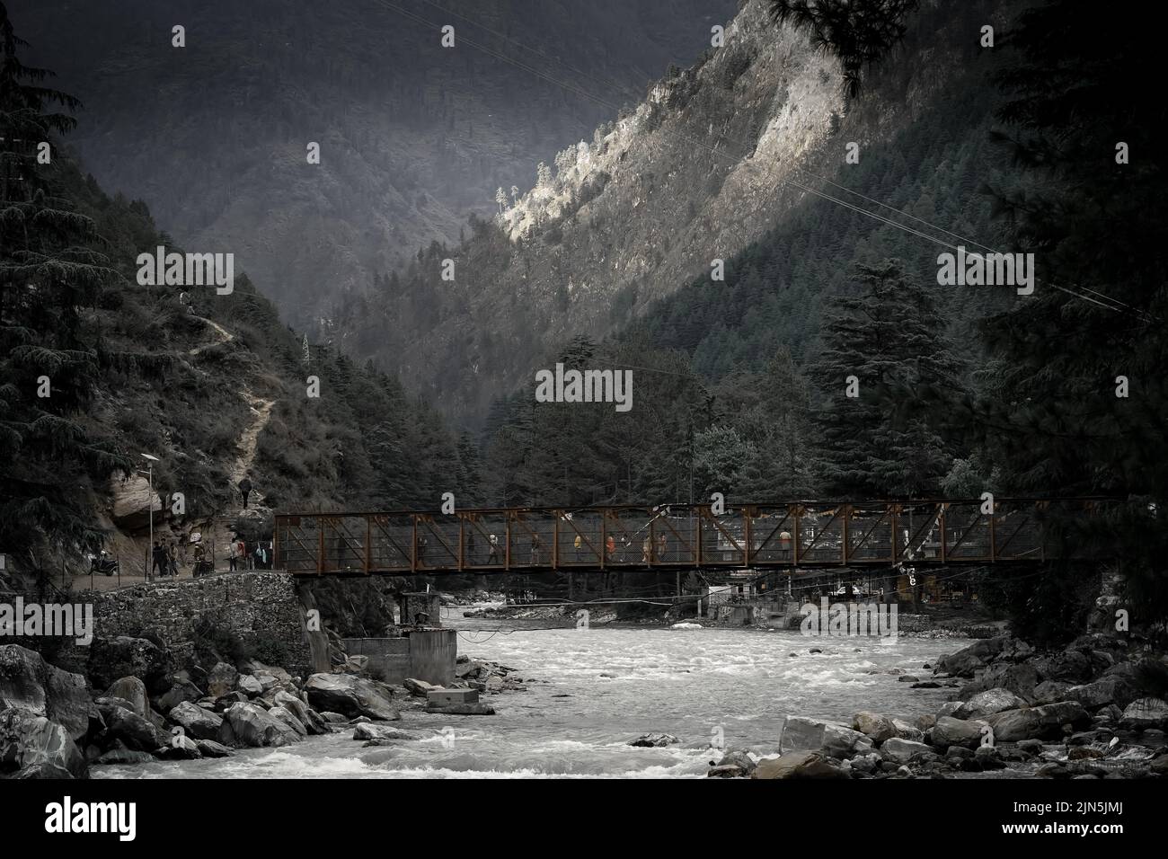 Photo of a bridge with snow-capped mountains in the background and a ...