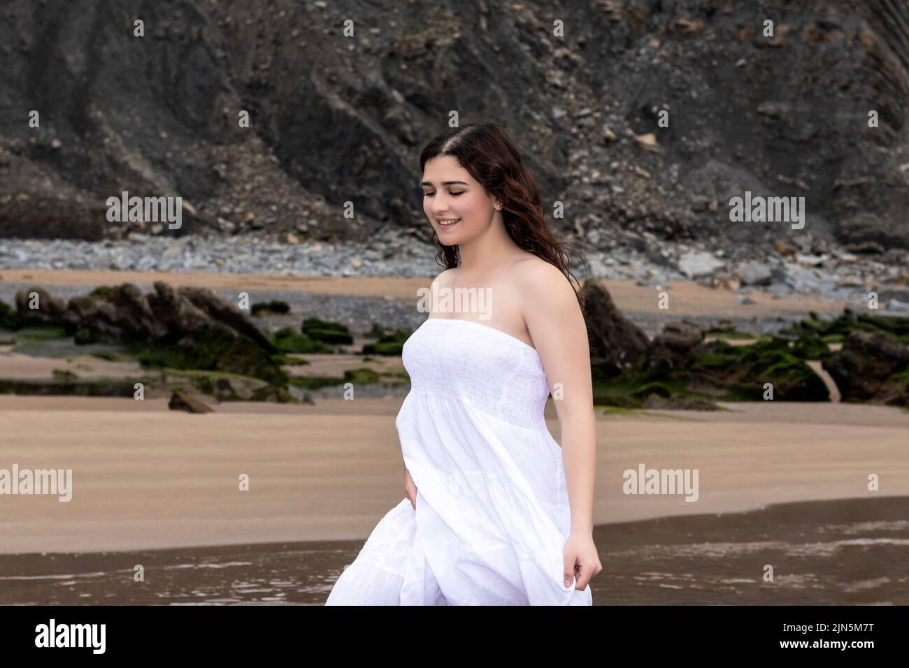 young woman in white dress walking on the beach Stock Photo - Alamy