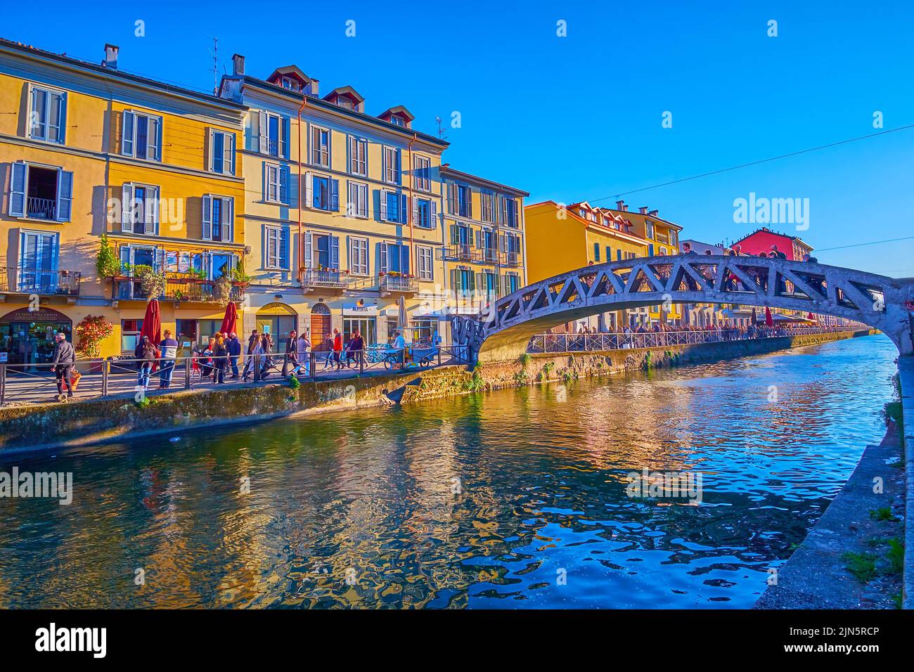 MILAN, ITALY - APRIL 9, 2022: The rippled waters of Naviglio Grande Canal with Alda Merini Bridge and colorful housing of Navigli neighborhood around Stock Photo