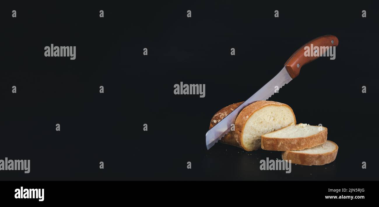 Sliced fresh bread and cutting knife on black background Stock Photo