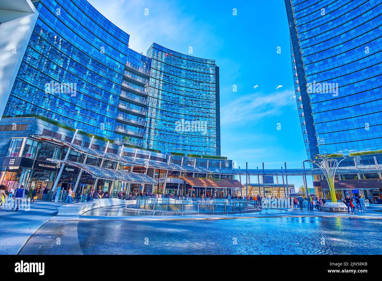 MILAN, ITALY - APRIL 9, 2022: Modern Piazza Gae Aulenti with its large pool is the most photogenic place for shopping and leisure strolls outside city Stock Photo