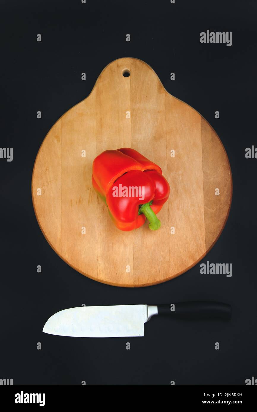 Cut red pepper on wooden board and black background Stock Photo