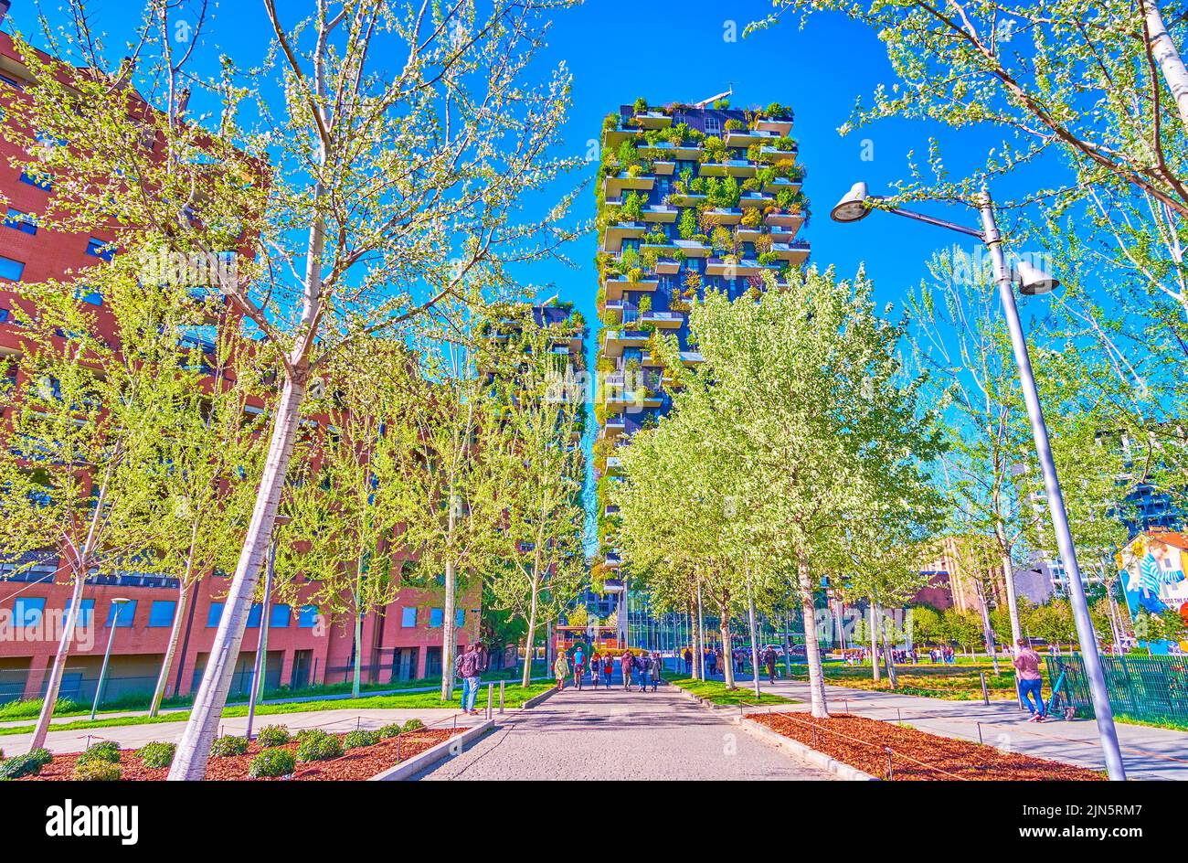 The shady alley of Biblioteca degli Alberi Park with famous residential Bosco Verticale buildings on background, Milan, Italy Stock Photo