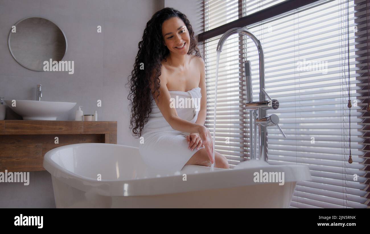 Attractive young happy woman taking bath washing hands under running