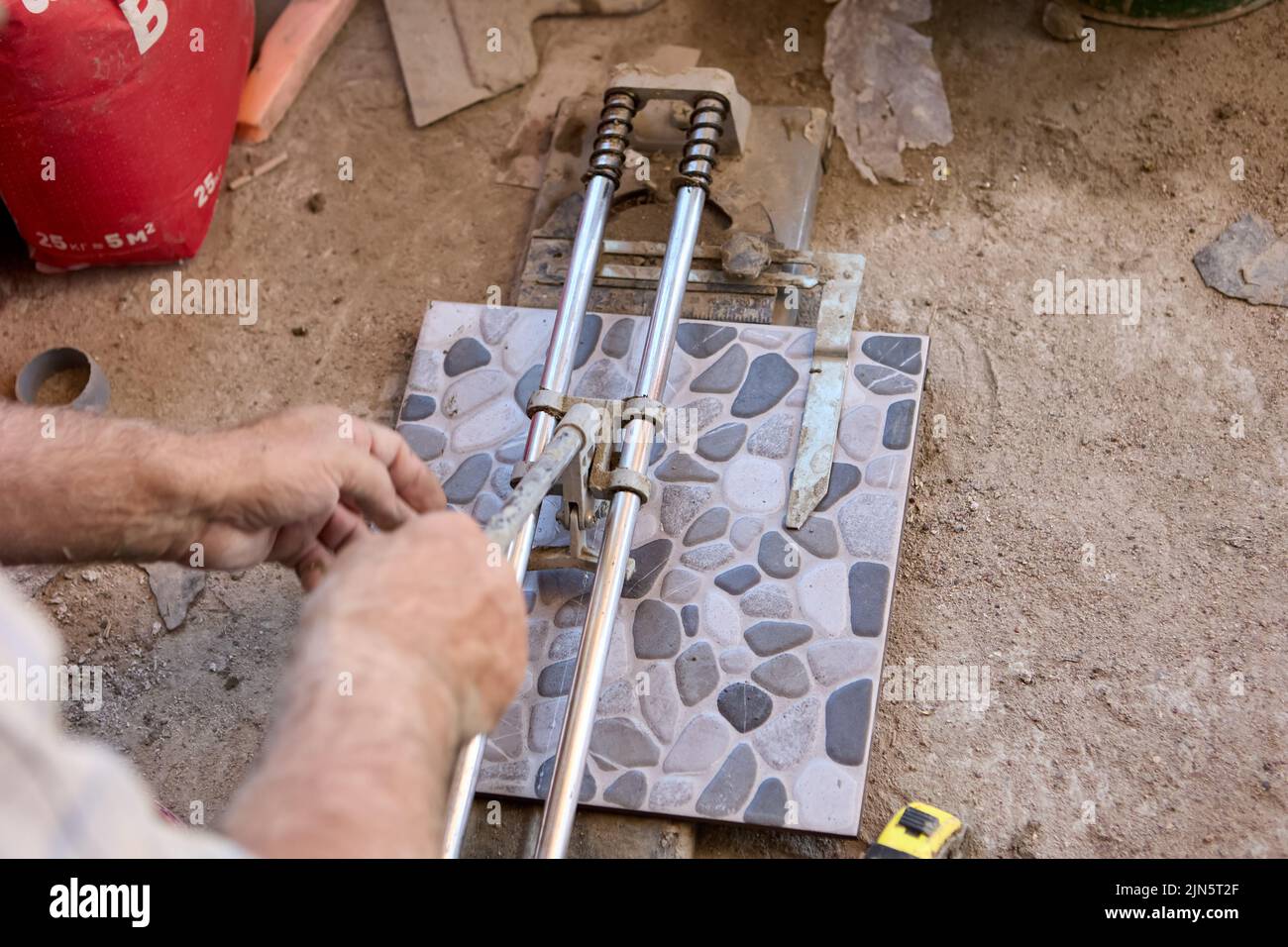 Builder uses tile cutter to cut floor tiles while finishing new home