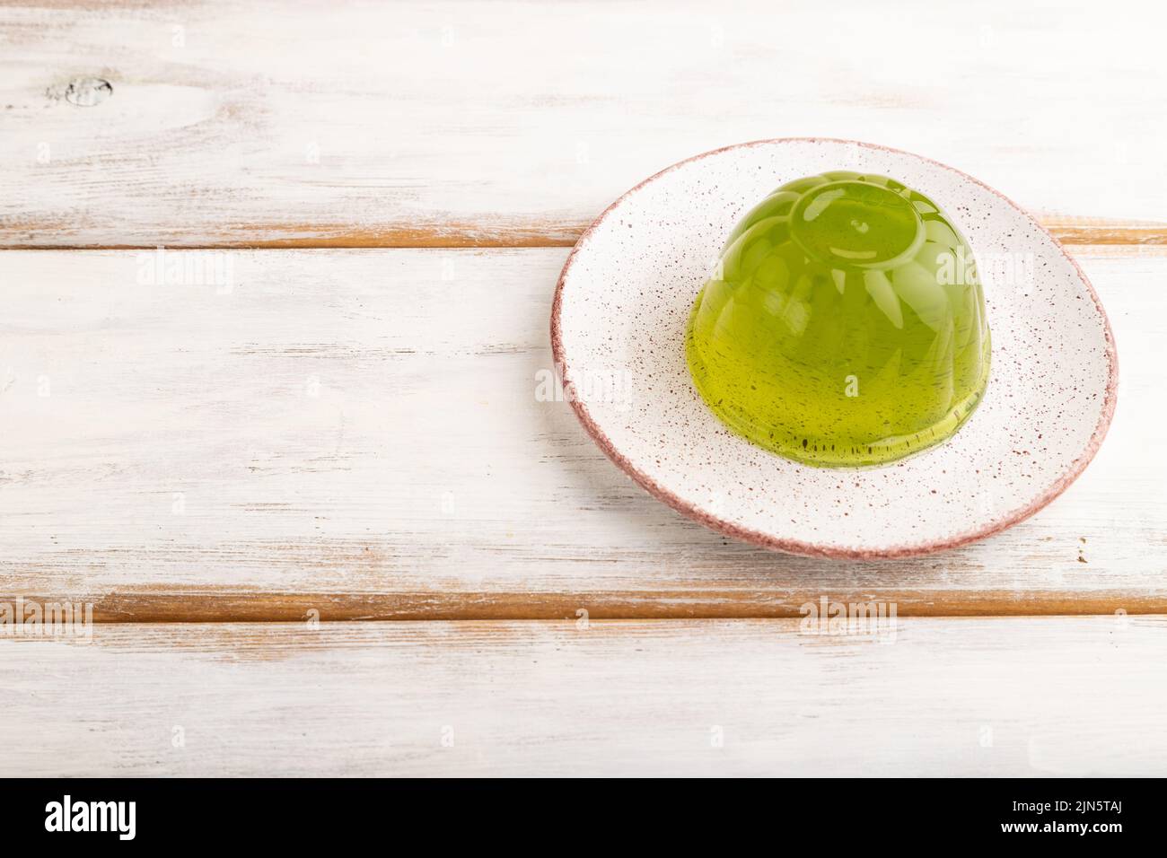 Mint green jelly on white wooden background. side view, copy space