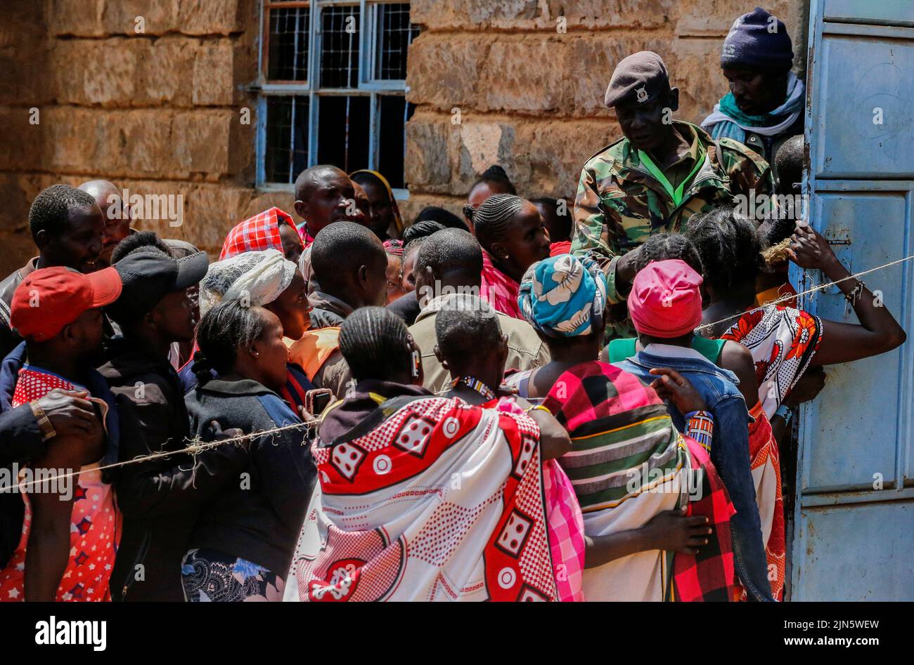 A police officer controls Maasai traditional people at a polling centre before casting their ballots during the general election by the Independent Electoral and Boundaries Commission (IEBC) at Ewaso Kedong primary school, in Kajiado county, Kenya August 9, 2022. REUTERS/Thomas Mukoya Stock Photo