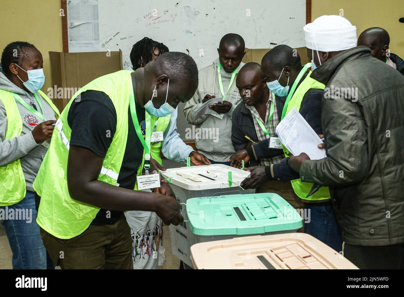 Officials of The Independent Electoral and Boundaries Commission (IEBC) seal ballot boxes as party agents observe during Kenya's general election. Kenyans began voting on Tuesday morning, August 9, 2022, to elect their preferred president and members of both the national and county assemblies. In the contested presidential election, a neck-and-neck race is expected between Azimio La Umoja presidential candidate, Raila Odinga, 77, and Kenya Kwanza Allianceís William Ruto, 55, in an election with four presidential candidates; others being David Mwaure of The Agano Party and George Wajakhoyah rep Stock Photo