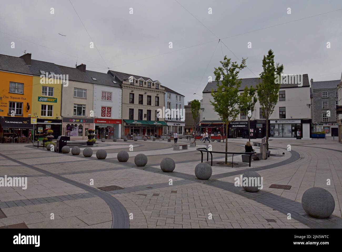 People sat at tables outside traditional Irish pubs in the square at Dominick Street, Tralee, County Kerry, Ireland, July 2022 Stock Photo