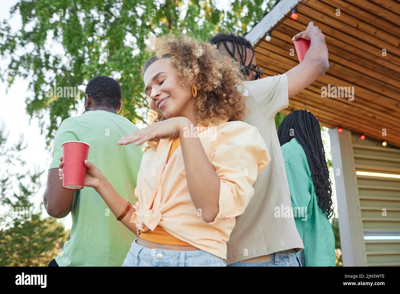 Waist p portrait of carefree young woman dancing outdoors at Summer party Stock Photo