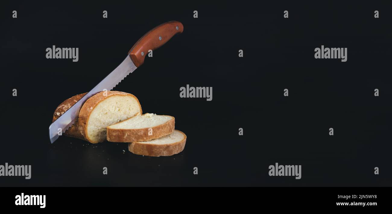 Cut fresh bread with a knife. Large kitchen knife cuts freshly baked, fragrant, crisp rye bread, a symbol of food. Stock Photo