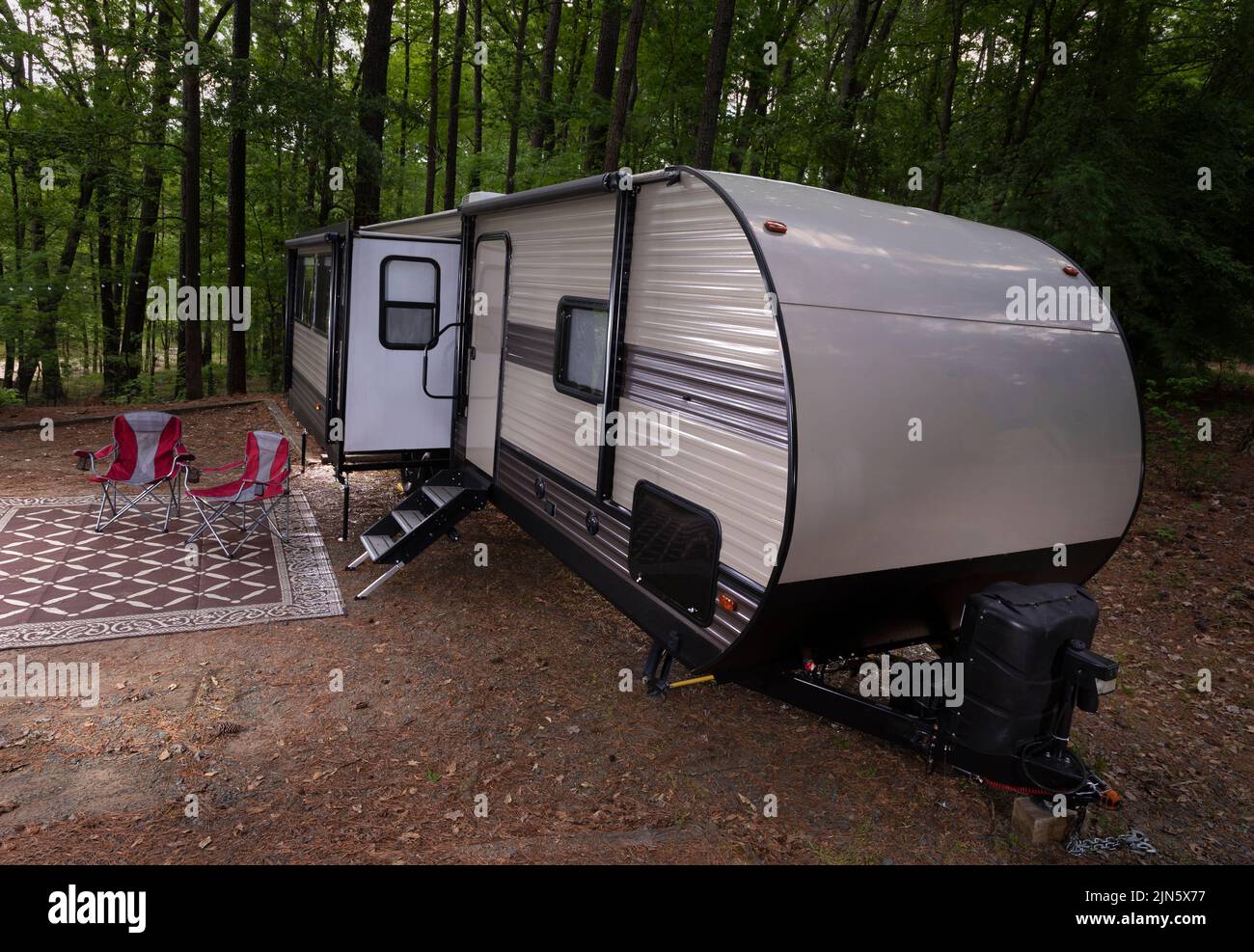 Camper trailer at a Jordan Lake North Carolina campsite with two red chairs waiting Stock Photo