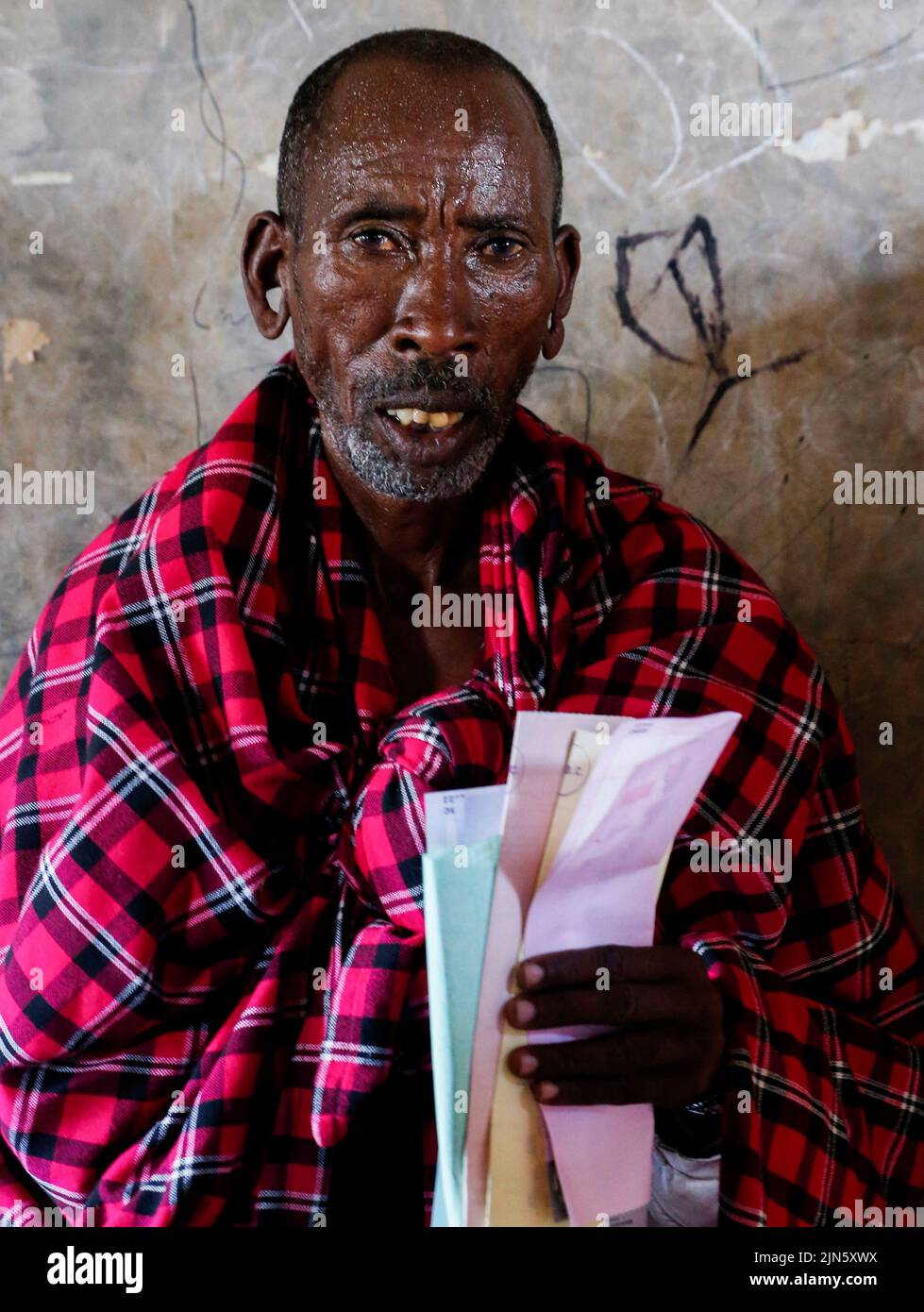 A Maasai traditional man waits near a voting booth at a polling centre before casting his ballot during the general election by the Independent Electoral and Boundaries Commission (IEBC) in Ewaso Kedong primary school, in Kajiado county, Kenya August 9, 2022. REUTERS/Thomas Mukoya Stock Photo