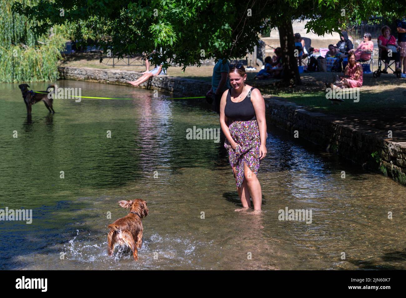Bourton on the Water, Glocs, UK. 9th Aug, 2022. People are out and about enjoying the sun by the River Windrush in Bourton on the Water, Glocestershire, as temperatures are set to rise this coming week. Credit: Peter Lopeman/Alamy Live News Stock Photo