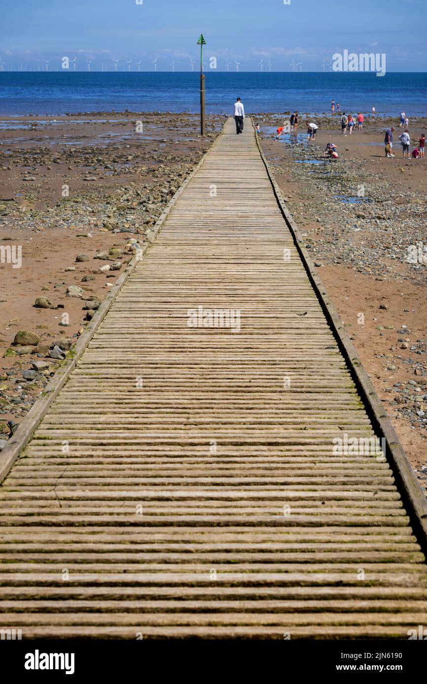 A lone figure at the end of a pier, alone in a crowd. Stock Photo