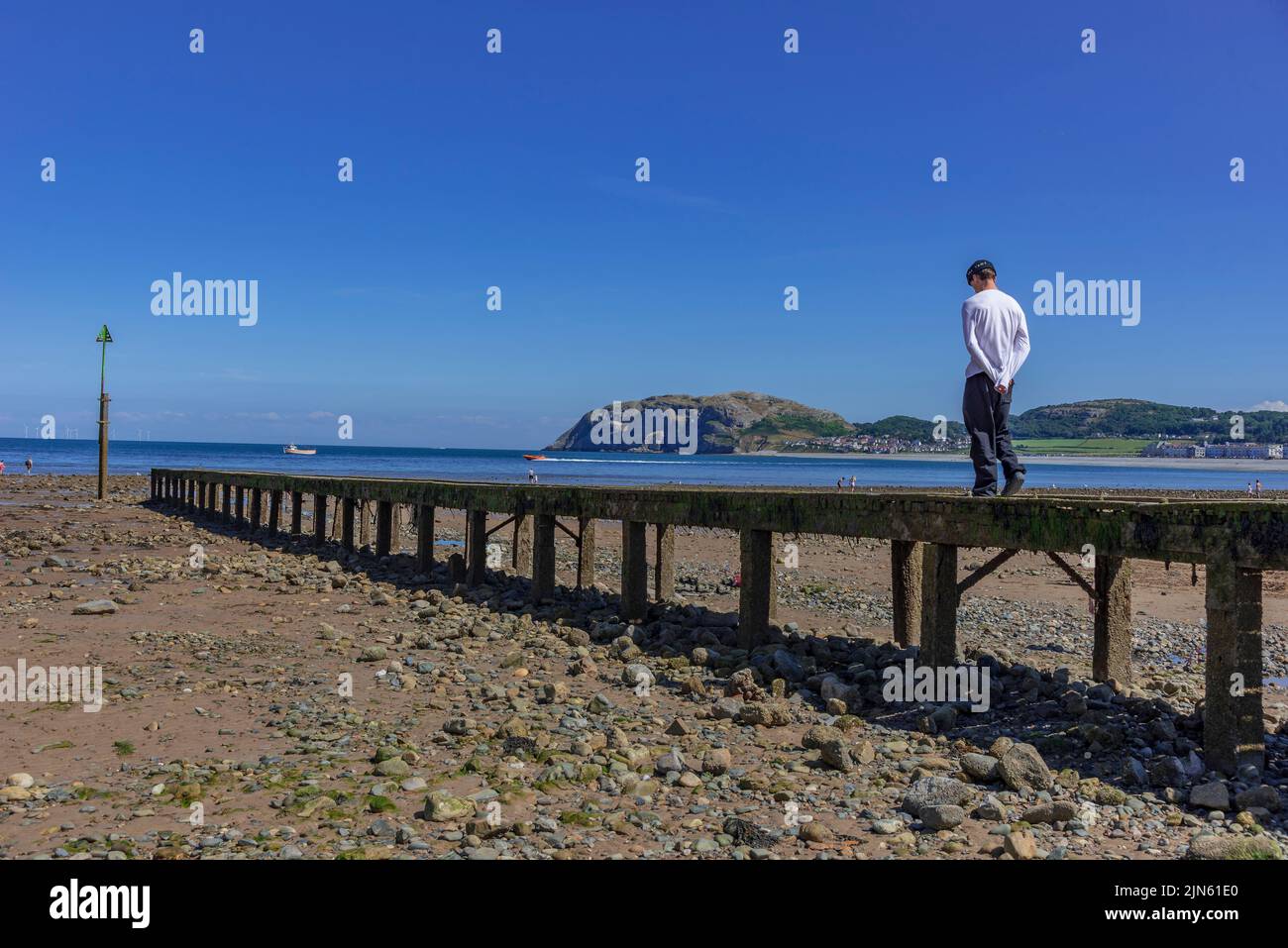A lone figure on a pier for small boats in Llandudno Stock Photo