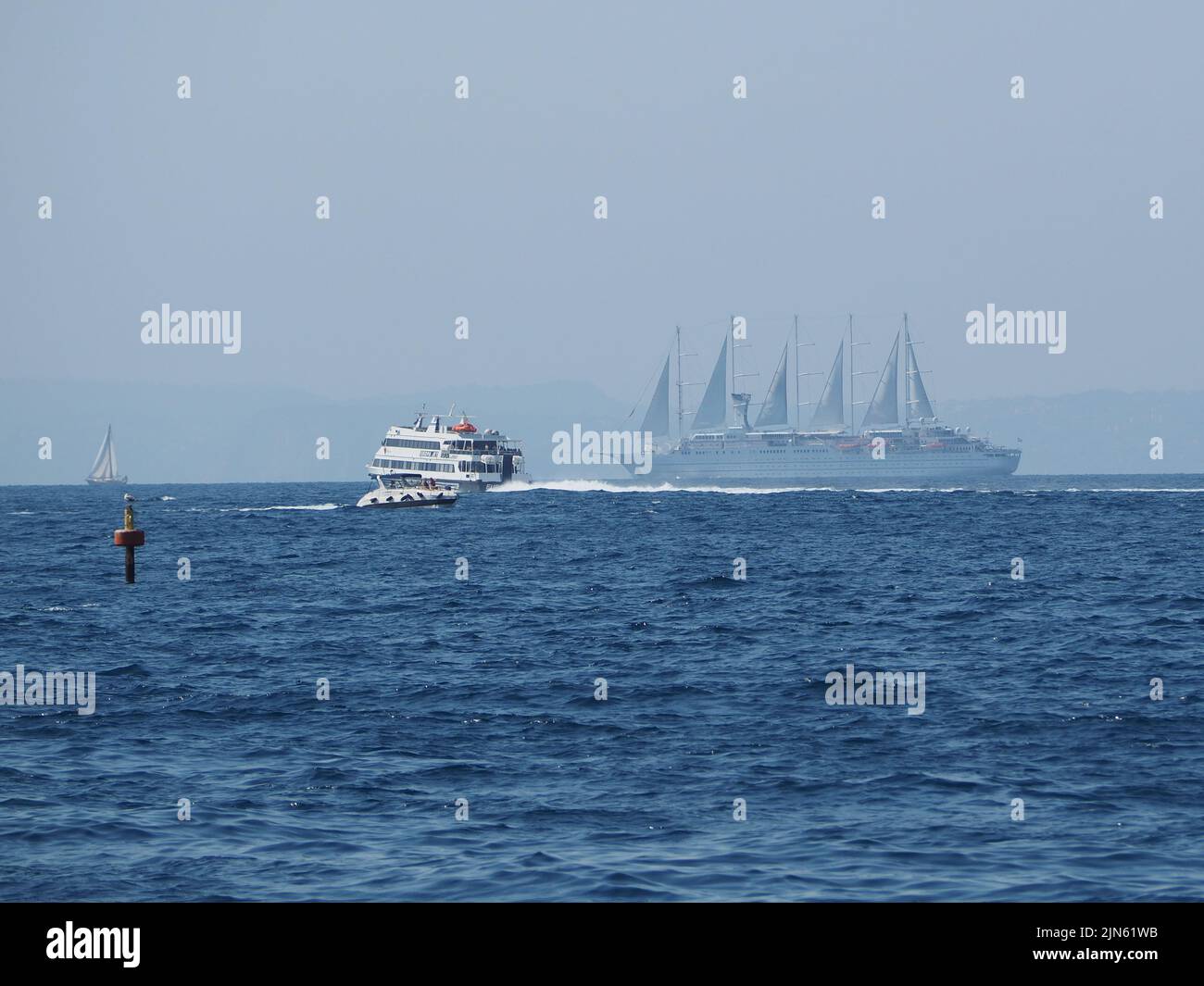 Traffic on the Mediterranean sea near Sorrento including a ferry and a large cruise ship with sails. Stock Photo
