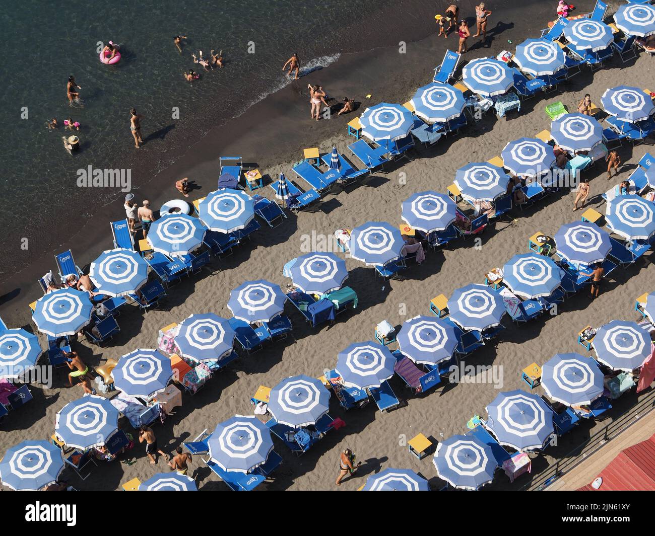 Many blue parasols on the narrow beach in Sorrento, Campania, Italy. Stock Photo
