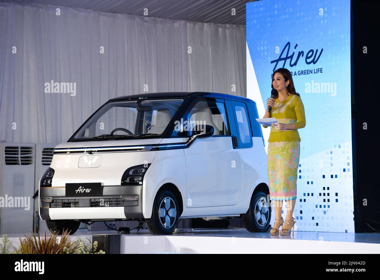 BEKASI, Aug. 9, 2022 (Xinhua) -- A hostess briefs people on Wuling Air EV during the roll-out ceremony at Wuling's production factory in Bekasi, West Java province, Indonesia, Aug. 8, 2022. SAIC-GM-Wuling (SGMW), a major Chinese automobile manufacturer, through its local unit SGMW Motor Indonesia (Wuling), on Monday launched here its production of the electric vehicle in Indonesia, named Wuling Air EV. (Xinhua/Xu Qin) Stock Photo