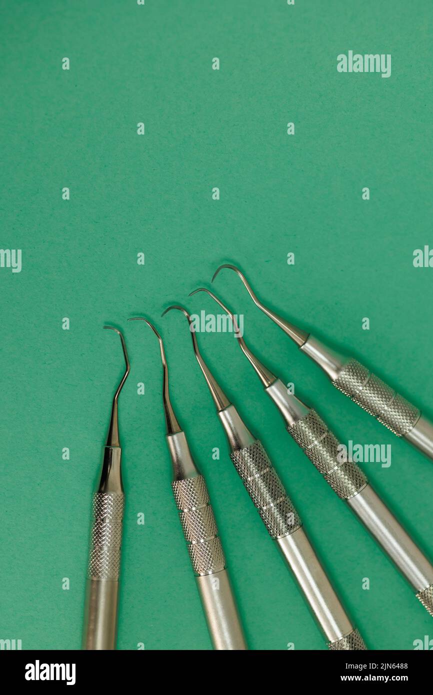 Dental scaler and probes on green background, stainless medical