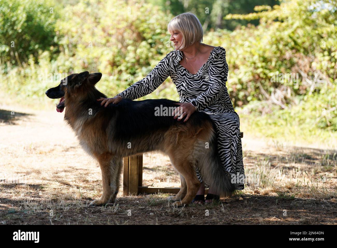 NHS worker Maxine Lloyd from Kettering and her German Shepherd dog Rosco at Barton Hall Hotel in Kettering, Northamptonshire. Maxine won £1 million playing one of the National Lottery's instant win games, which became a double-celebration when she received the all-clear for breast cancer a few days later. Picture date: Tuesday August 9, 2022. Stock Photo