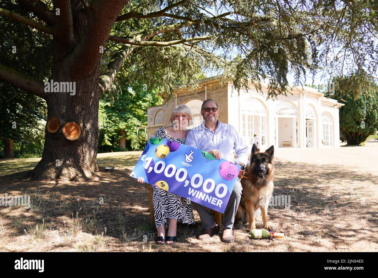 NHS worker Maxine Lloyd, her fiance Wayne Tilbury from Kettering and their German Shepherd dog Rosco, celebrate her £1 million win on one of the National Lottery's instant win games at Barton Hall Hotel in Kettering, Northamptonshire, which became a double-celebration when she received the all-clear for breast cancer a few days later. Picture date: Tuesday August 9, 2022. Stock Photo