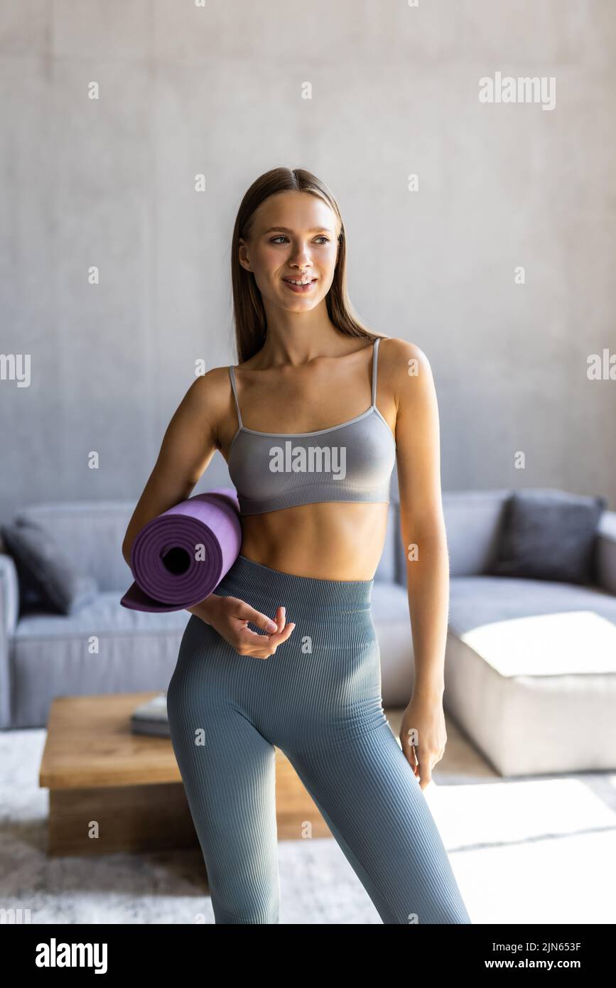 Portrait of woman wearing sportswear holding a yoga or fitness mat. Stock Photo