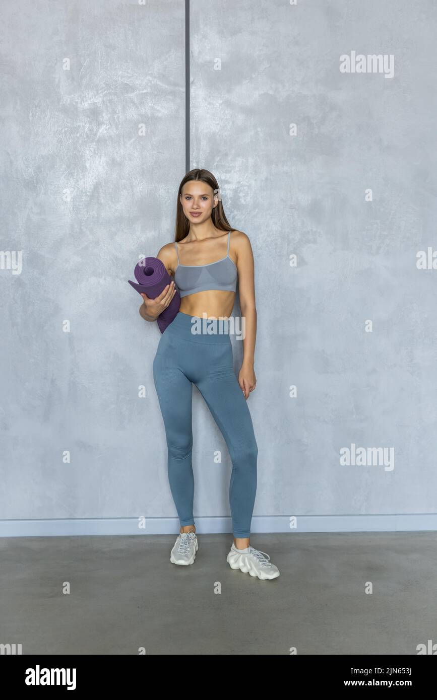 Sports girl holding a fitness mat in her hands at home Stock Photo