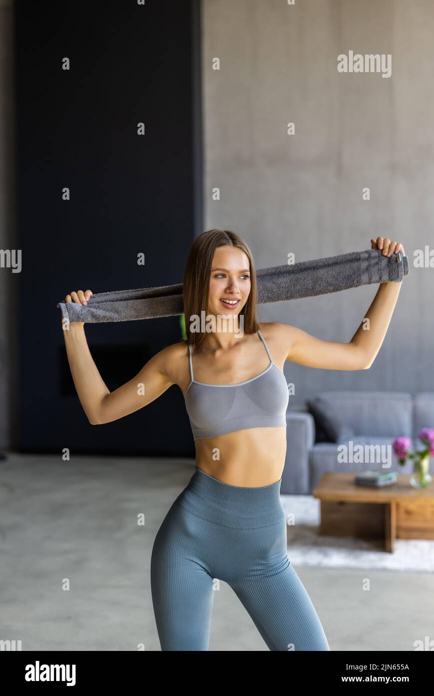 Active athlete girl have end of aerobics intense practice hold towel on shoulder relax in house like fitness studio Stock Photo